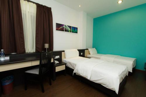 a bedroom with two beds and a desk with a chair at Aurora Boutique Hotel in Bahau