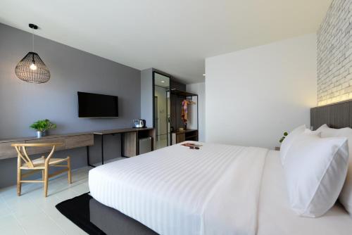 a bedroom with a large white bed and a desk at Ruenthip Pattaya in Pattaya North