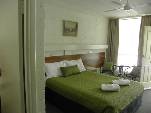 a bedroom with a green bed with two dishes on it at 7th Street Motel in Mildura