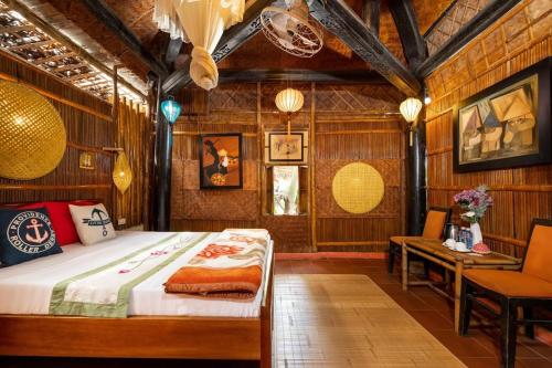 a bedroom with a bed and a table and chairs at Under The Coconut Tree Hoi An Homestay in Hoi An