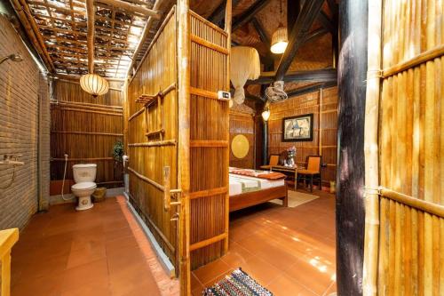 a bathroom with a toilet and a wooden wall at Under The Coconut Tree Hoi An Homestay in Hoi An
