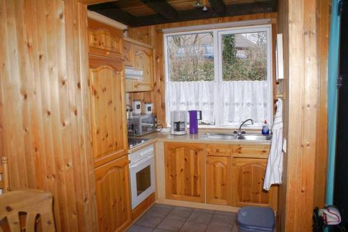 eine Küche mit Holzschränken, einem Waschbecken und einem Fenster in der Unterkunft Ferienhaus Anke nur für Urlauber! in Bremke