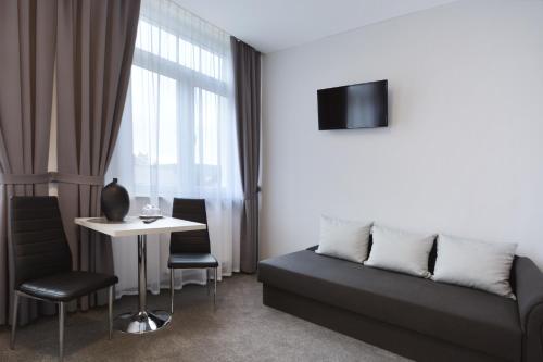 a living room with a couch and a table and a tv at Hotel Roztocze in Zwierzyniec