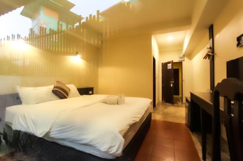a bedroom with a large bed with white sheets at Baan Pordeedin in Chiang Rai