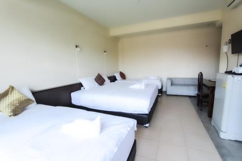 a hotel room with two beds and a refrigerator at Baan Pordeedin in Chiang Rai