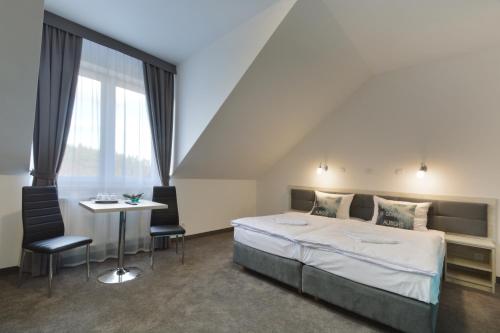 a bedroom with a bed and a table and chairs at Hotel Roztocze in Zwierzyniec