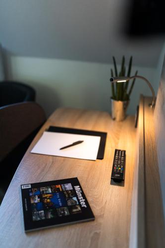 a desk with a pen and a remote control on it at Hotel Hüerländer in Münster