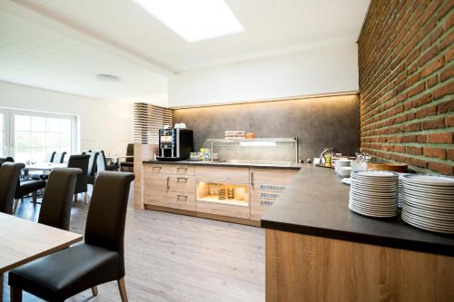 uma cozinha com mesas e cadeiras e uma parede de tijolos em Hotel Hüerländer em Münster
