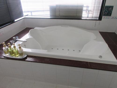 eine weiße Badewanne im Bad mit Flaschen auf der Theke in der Unterkunft ウォーターゲート鹿児島 in Kagoshima