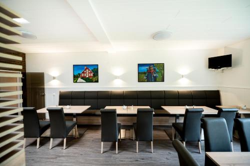 uma sala de jantar com mesas e cadeiras e uma televisão em Hotel Hüerländer em Münster