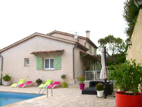 une maison avec des chaises roses et une piscine dans l'établissement Le Jacaranda, à Villeneuve-Loubet