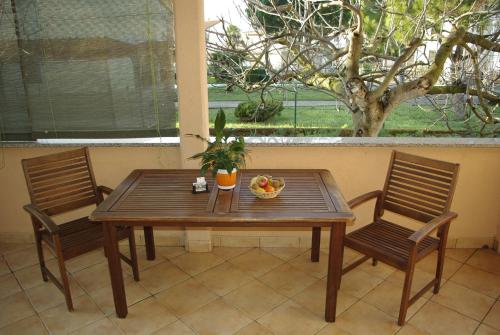 a wooden table with two chairs and a bowl of fruit at Apartments & Rooms BARBARA in Umag