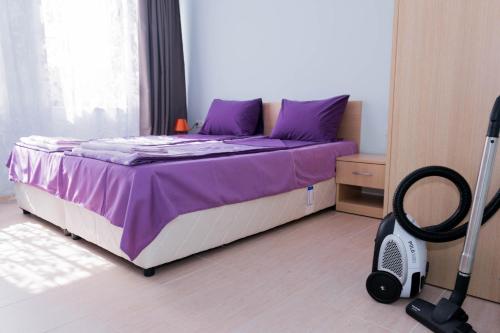 a bedroom with a bed with purple sheets and a vacuum at Апартамент и студио Фантазия in Sozopol