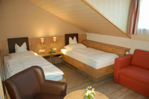 um pequeno quarto com 2 camas e uma cadeira em Gasthof Gruber em Fridolfing