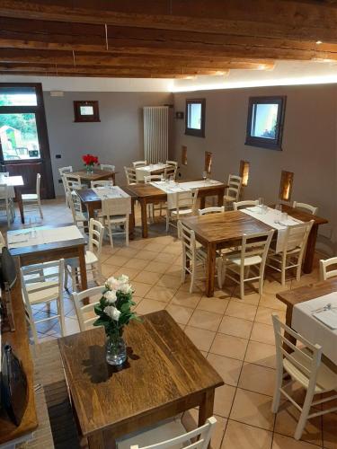 a restaurant with wooden tables and chairs and flowers on tables at Locanda Merlaschio in Faenza