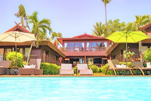 a house with chairs and umbrellas next to a swimming pool at Erawan Villa Hotel in Bangrak Beach