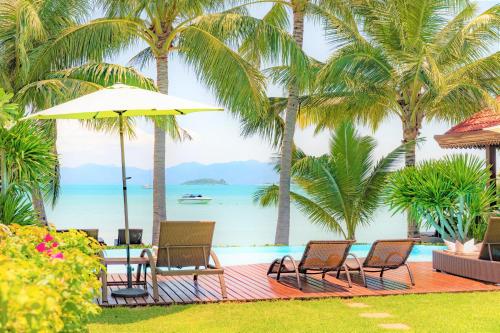 a pool with palm trees and chairs and a table and umbrella at Erawan Villa Hotel in Bangrak Beach