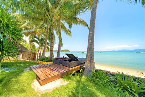 a bench on the beach with palm trees at Erawan Villa Hotel in Bang Rak Beach