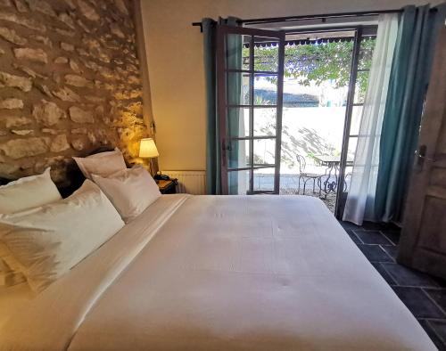 ein Schlafzimmer mit einem großen weißen Bett und einer Glasschiebetür in der Unterkunft Hôtel Sous les Figuiers - Piscine, parking, centre ville in Saint-Rémy-de-Provence