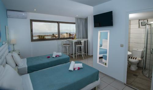 a hotel room with two beds and a bathroom at Kastro Beach Apartments in Malia