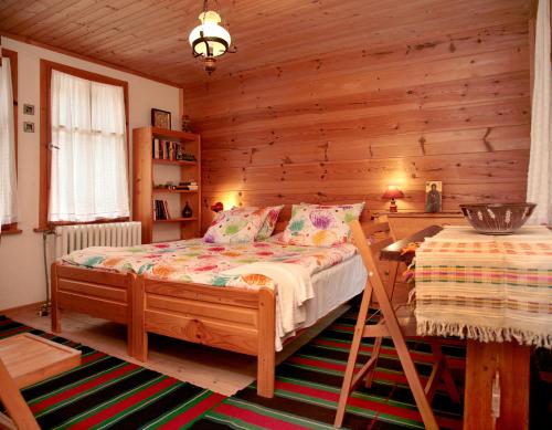 a bedroom with a bed and a wooden wall at Къща край реката - Триград in Trigrad