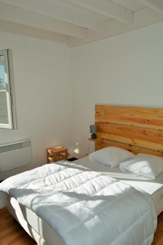 - une chambre avec un grand lit blanc et une tête de lit en bois dans l'établissement Bel appart T3 ,100 m de l’océan , centre ville, à Soulac-sur-Mer