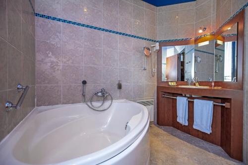 a bathroom with a large tub and a sink at Logis Hôtel Restaurant Gilles Moreau Laguiole in Laguiole