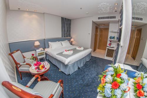 メッカにあるMontana Al Azizia Hotelのベッド、テーブル、椅子が備わるホテルルームです。