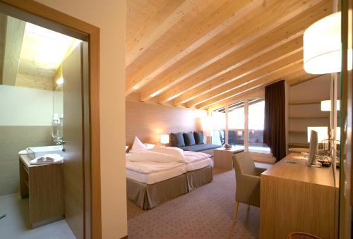 a hotel room with a bed and a desk at Quality Hosts Arlberg - Hotel Goldenes Kreuz B&B in Sankt Anton am Arlberg