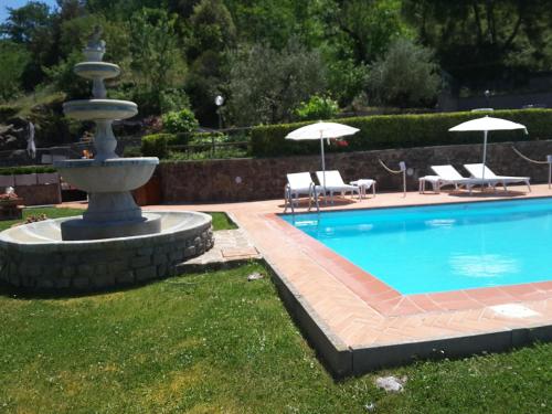 a swimming pool with a fountain and chairs and umbrellas at Rocca Palazzaccio in Impruneta