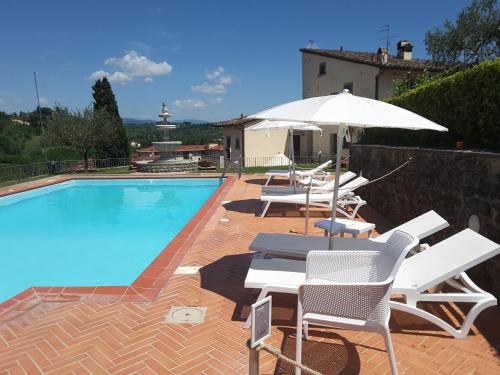 a swimming pool with lounge chairs and an umbrella at Rocca Palazzaccio in Impruneta
