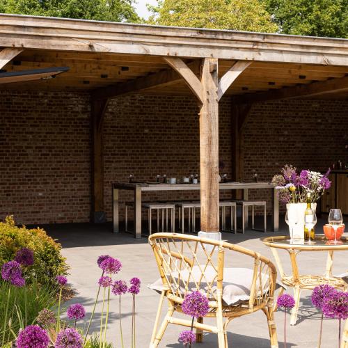 a patio with a table and chairs and purple flowers at Elvier B&B in Mol
