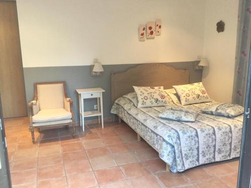 a bedroom with a bed and a chair at Le Patio Fleuri in Lorgues