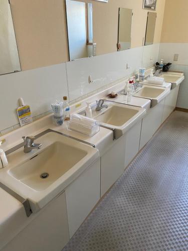 a bathroom with three sinks and two mirrors at Tengudaira Mountain Lodge in Tateyama