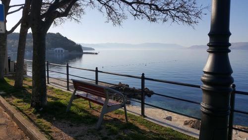 a bench next to a pole and a body of water at Apartments Adriatic 2 in Selce
