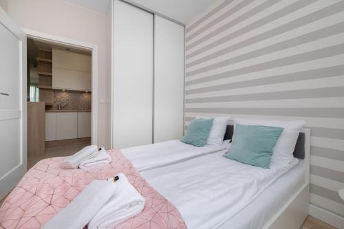 a bedroom with a large bed with pink and blue pillows at INA Rent - Tre Mare Apartamenty in Gdańsk
