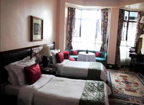 a hotel room with two beds and a couch at The Elgin Silver Oaks - Heritage Resort & Spa in Kalimpong