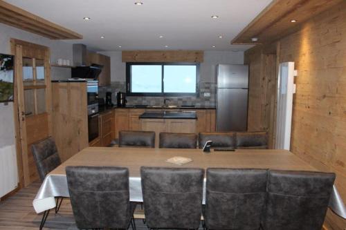 une cuisine avec une grande table et des chaises en bois dans l'établissement chalet bel horizon La Montagne Des Lamas, à La Bresse