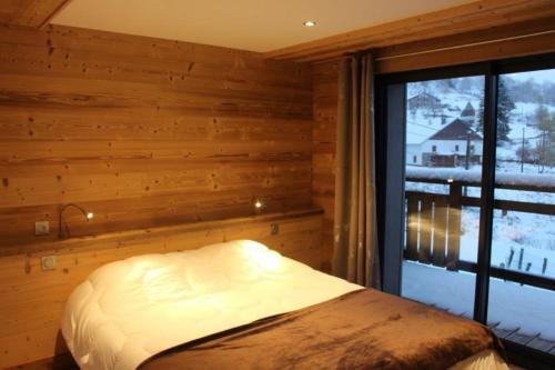 een slaapkamer met een bed en een groot raam bij chalet bel horizon La Montagne Des Lamas in La Bresse