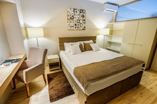 a bedroom with a bed and a desk and a chair at Annona Apartments in Bečej