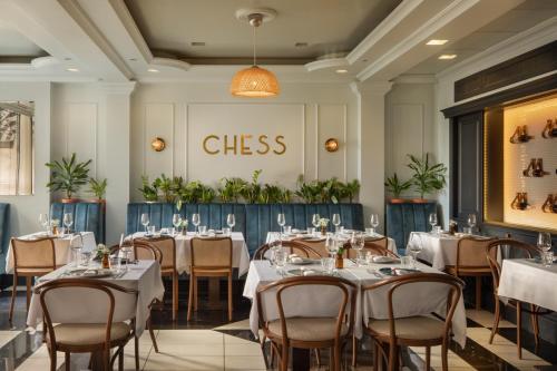 a restaurant with tables and chairs and a class sign on the wall at Queen's Court Hotel & Residence in Budapest
