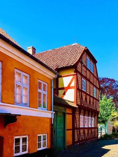 an orange building with a green door next to at Villa Wiegand - a room with a view in Holbæk