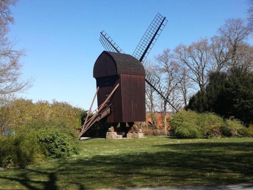 a large wooden windmill in a grass field at Villa Wiegand - a room with a view in Holbæk
