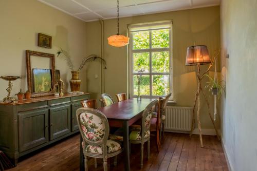 a dining room with a table and chairs and a window at Gastenverblijf Het Voorhuis in Herpen