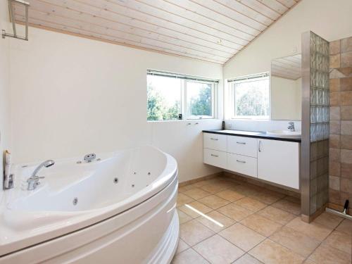Baño blanco con bañera y lavamanos en 9 person holiday home in V ggerl se, en Bøtø By
