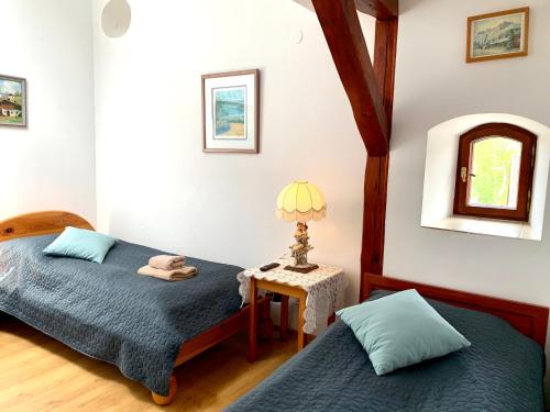 a bedroom with two beds and a table with a lamp at Kamienica Biała in Kazimierz Dolny