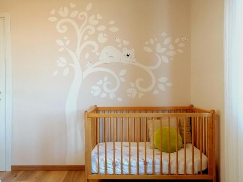 a nursery with a crib with a tree and two owls at Casa Artis in Gravedona