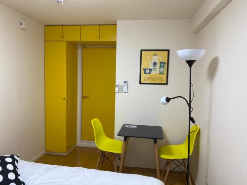 a bedroom with a desk and two yellow chairs at Melody Heim 2C in Tokushima