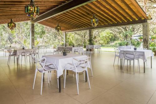 a dining room with white tables and chairs at Hotel Amate del Rio in Malinalco