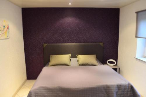 a bedroom with a large bed with a purple wall at Wohnung Ahorn in Riedstadt